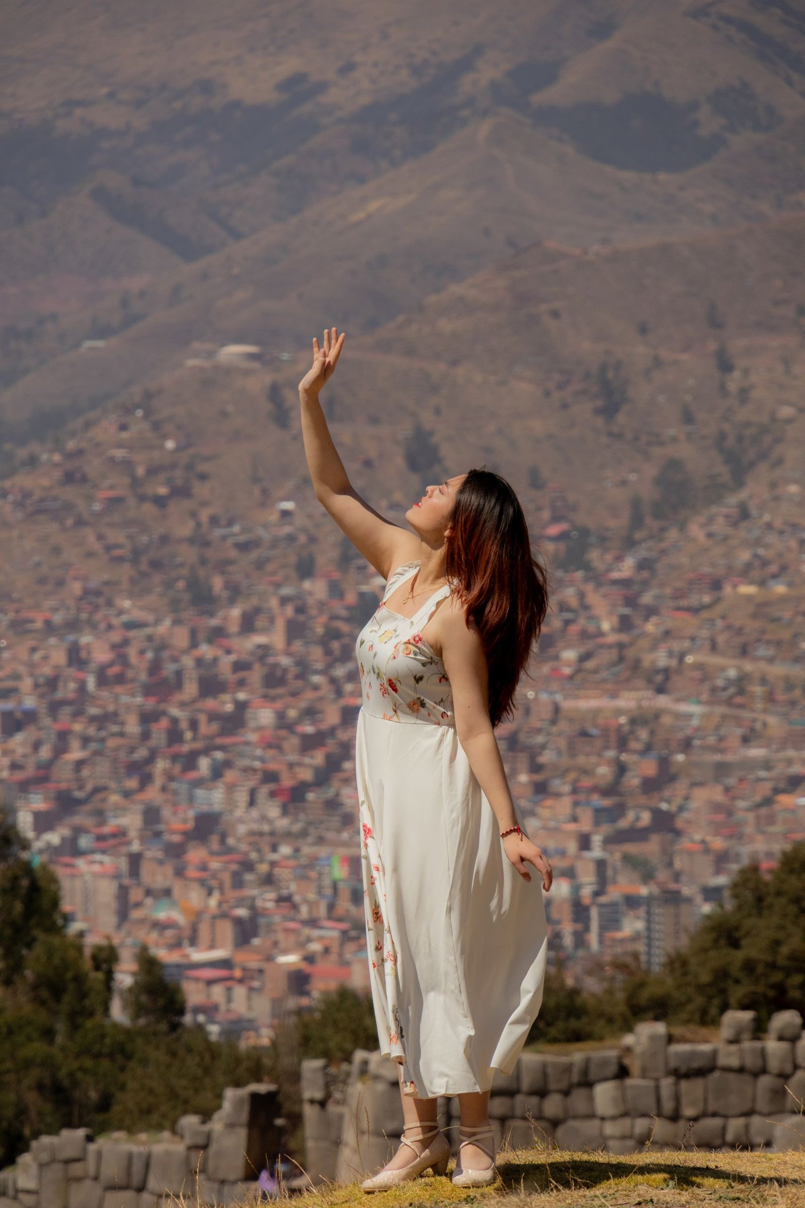 Woman in white dress poses gracefully against a mountain backdrop, capturing the essence of serenity and nature.